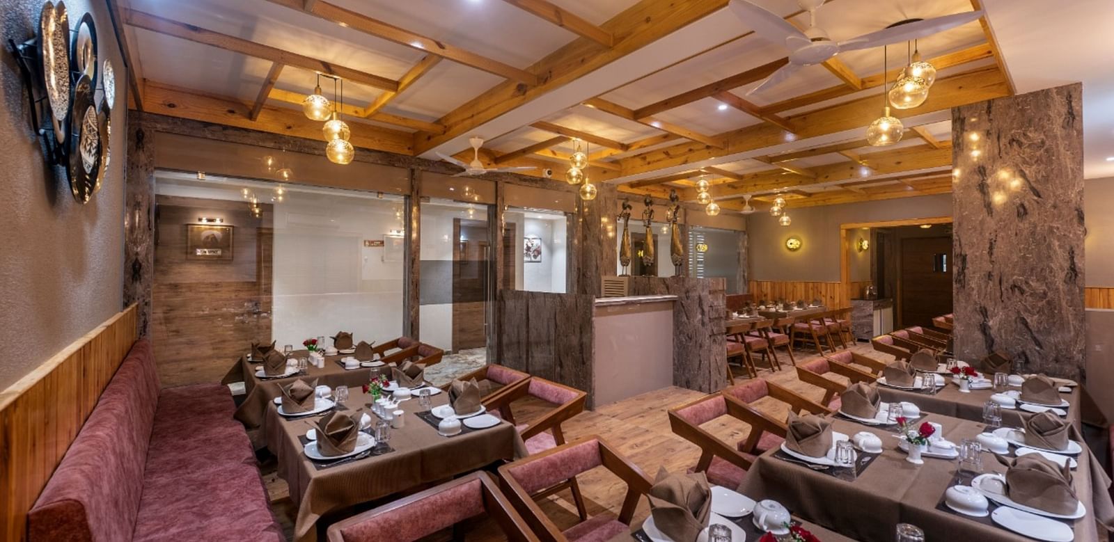 A dining area with multiple tables and chairs set under warm lighting at Angel Lords Eco Inn Amreli.
