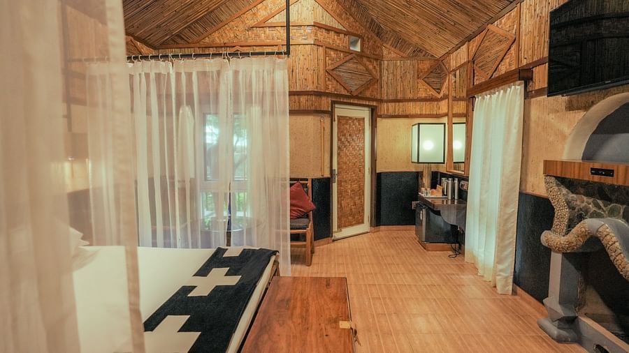 A bedroom with a bed, a lamp, and warm lighting, wooden interior - The Den Corbett Resort & Spa, Kumeria.