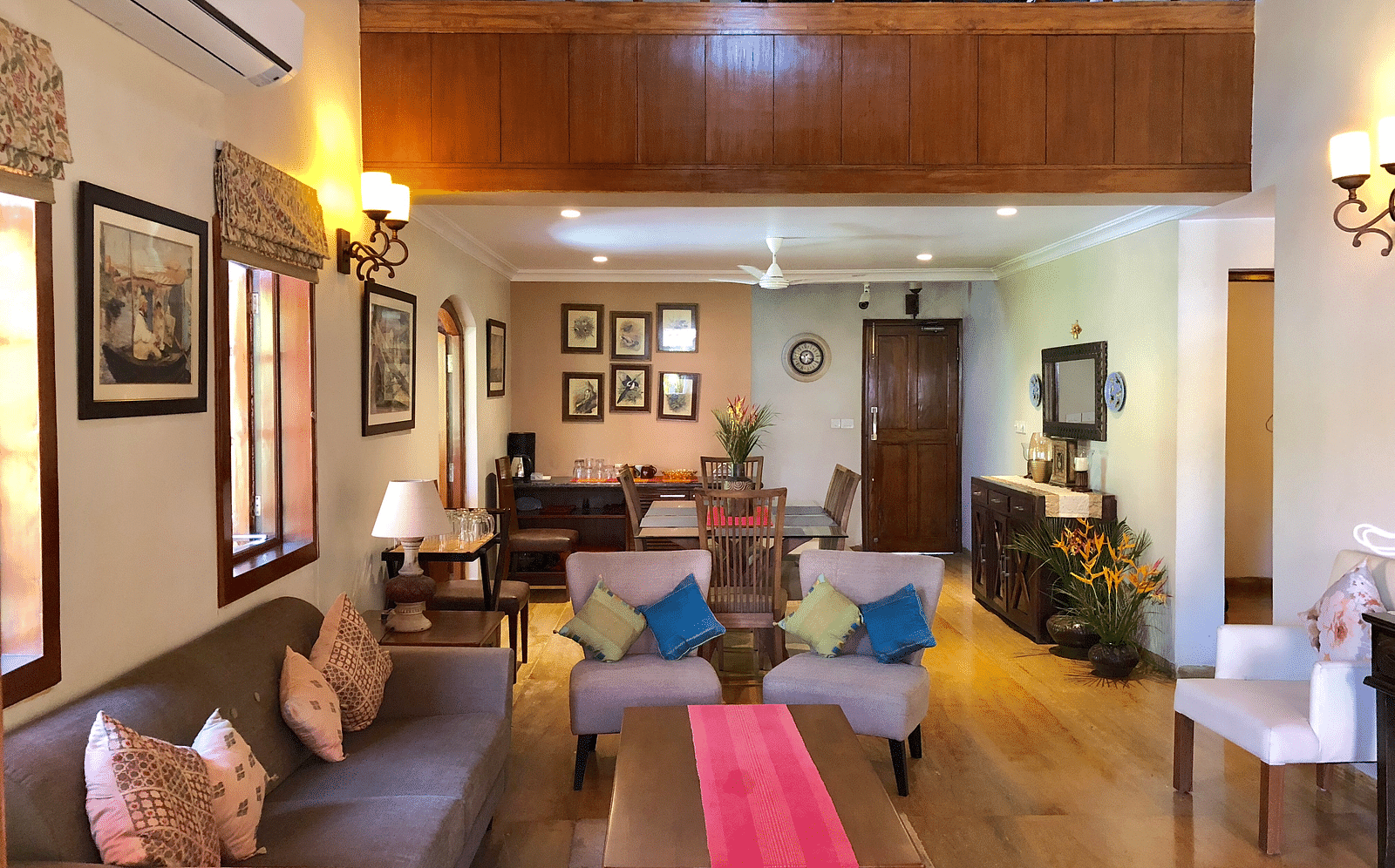 Living Area featuring a four seater sofa along with three couches behind which there is a six-seater dining table 
