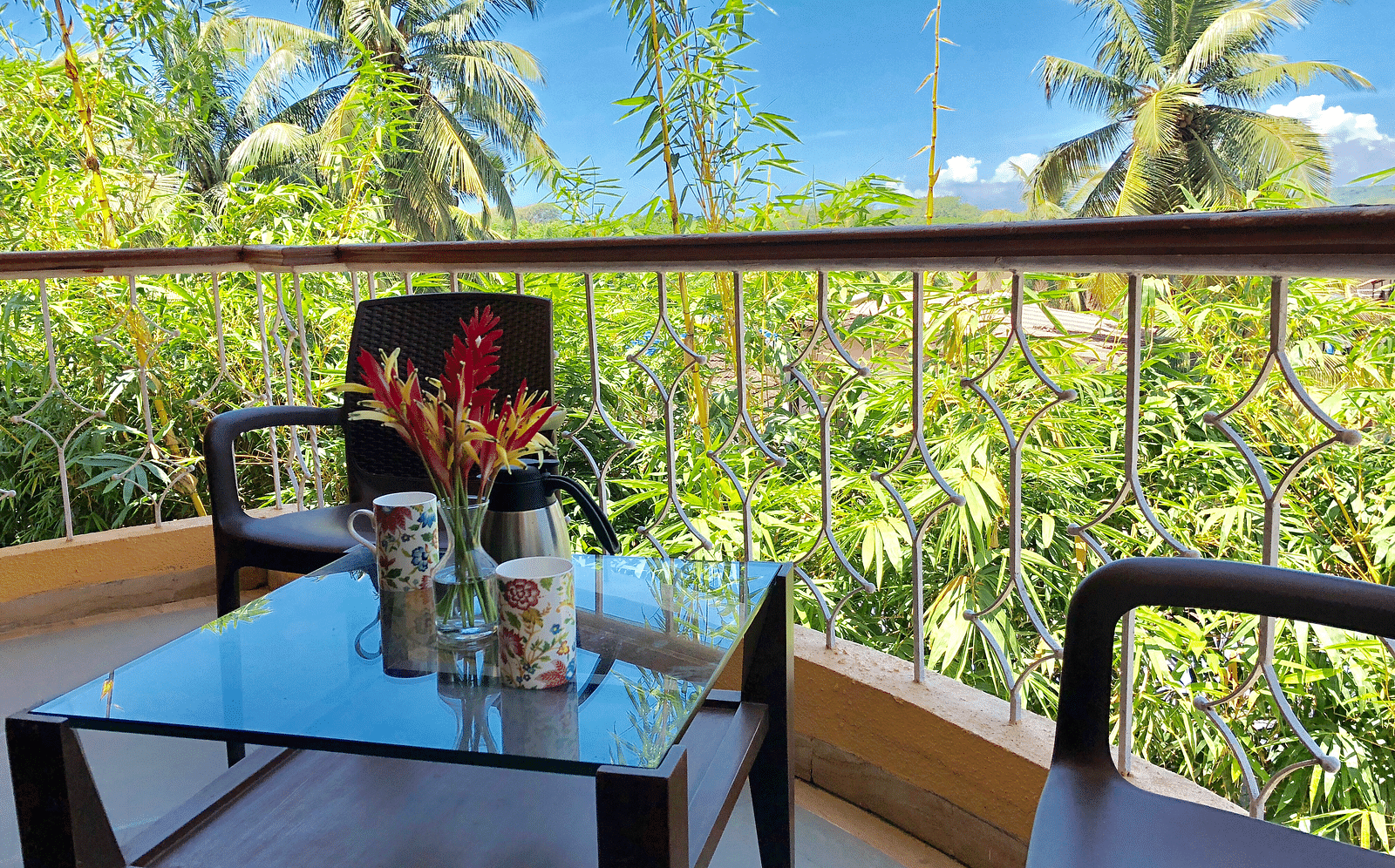 View of the greenery and clear sky from the balcony with a coffee table and a couple of chairs