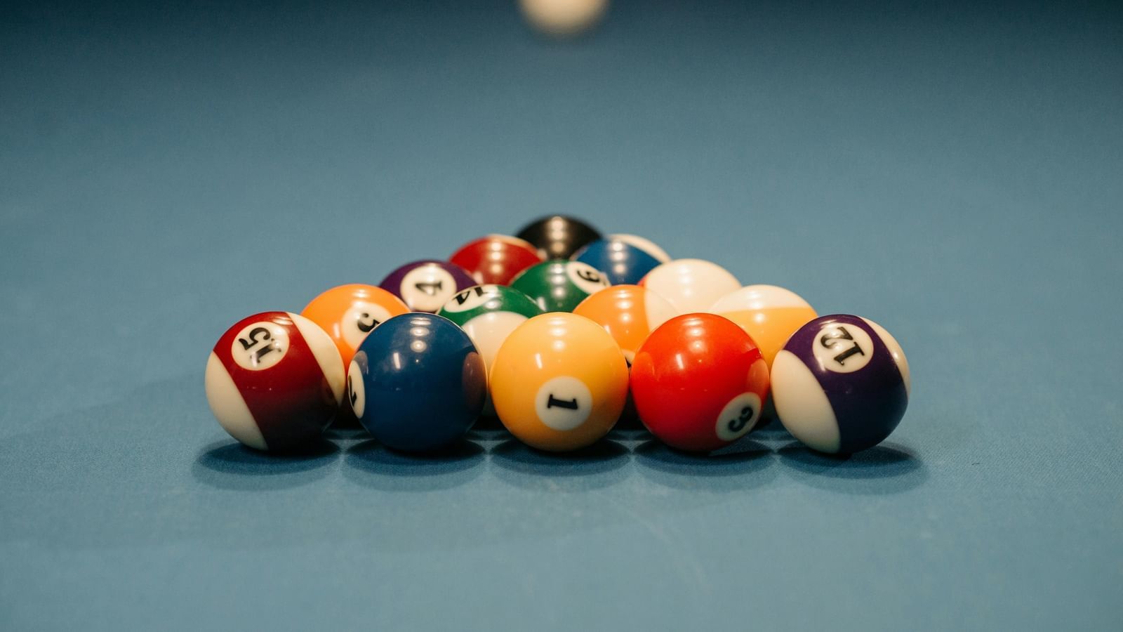 Pool balls arranged in a triangular rack on a blue pool table.