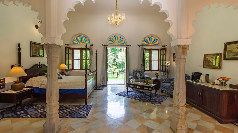 image of the Deluxe suite at Dev Shree, deogarh through the arched pillars featuring a double bed