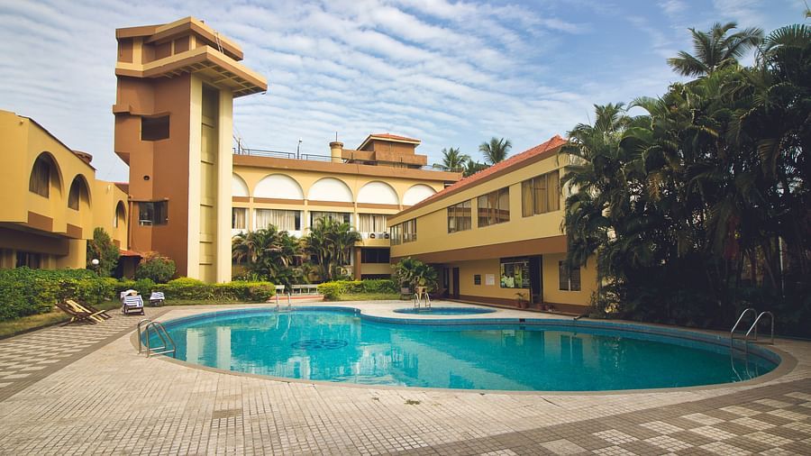 A view of the outdoor swimming pool at Paradise Isle Beach Resort, Udupi with the resort in the backdrop during the day