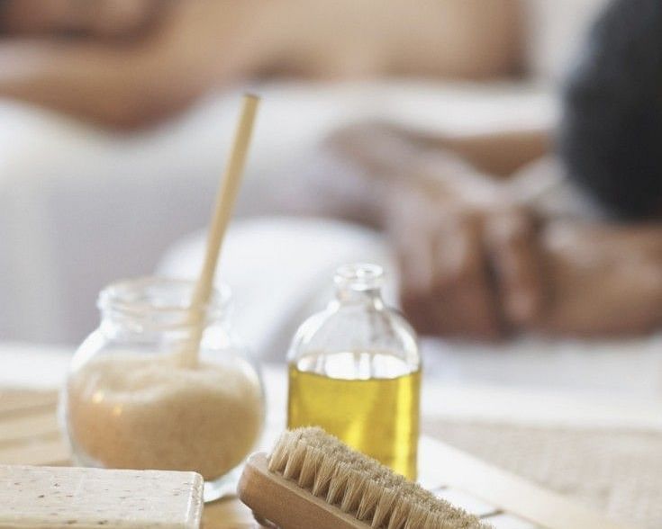 Close-up of a spa treatment setup featuring essential oils, a dry brush, and a relaxed ambiance.