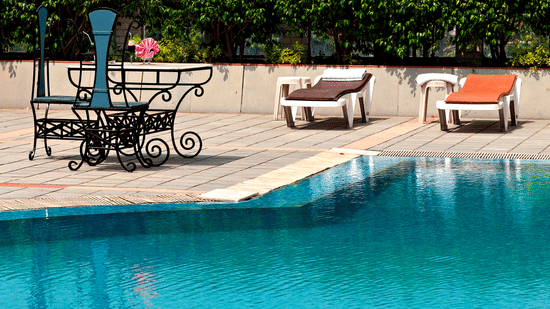 An outdoor swimming pool with sunbeds and scenic views of heritage architecture at a luxury hotel in Lucknow - Clarks Avadh, Luknow