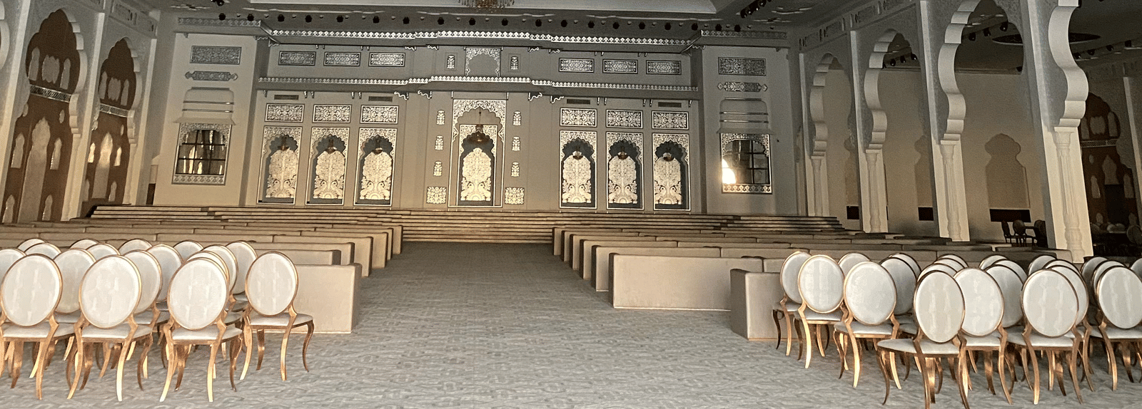 Large banquet hall with chandeliers, ornate ceiling and round dining tables at Beelwa Palace, Jaipur