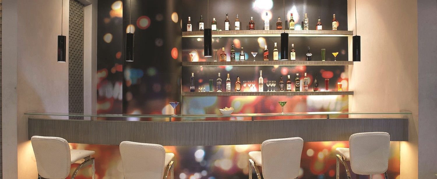 Image of zebra lounge at our hotel featuring a bar stand with chairs and bottles of alcohol | Mirage Hotel