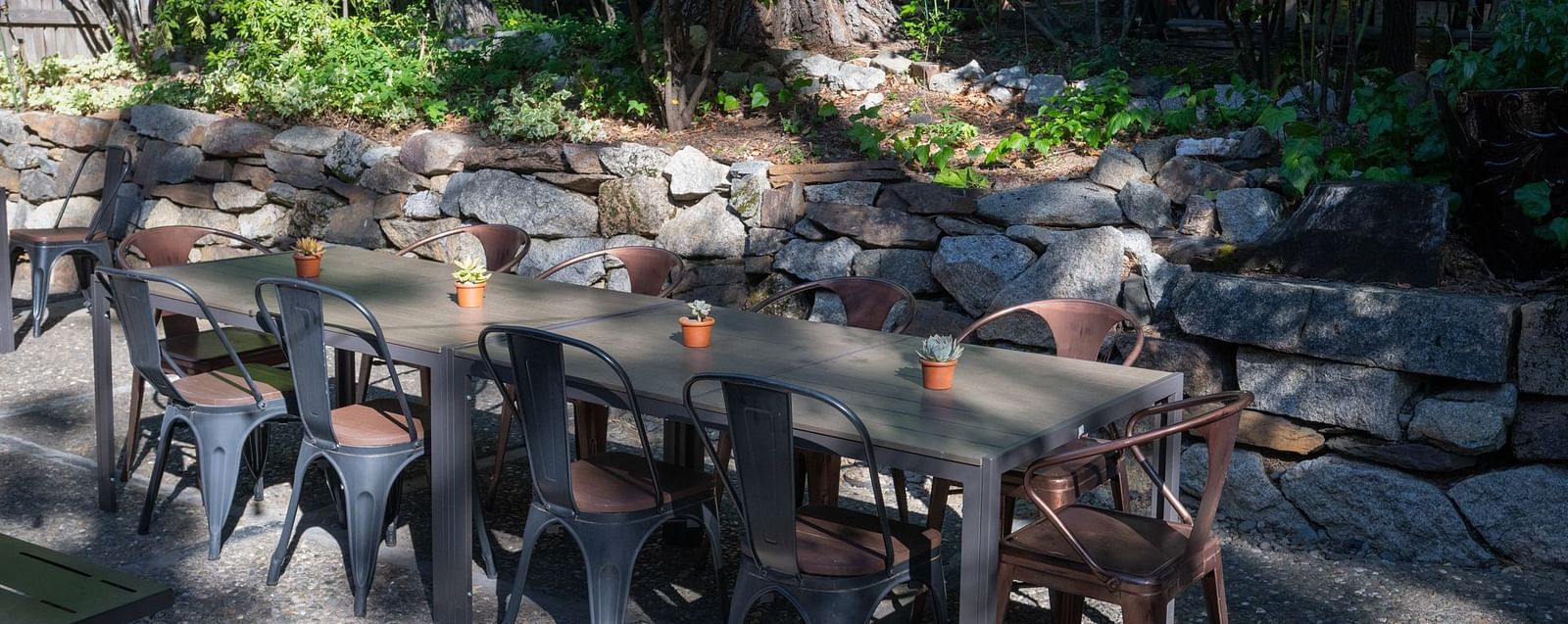 Outdoor dining setup with long communal tables among greenery at The Groveland Hotel.