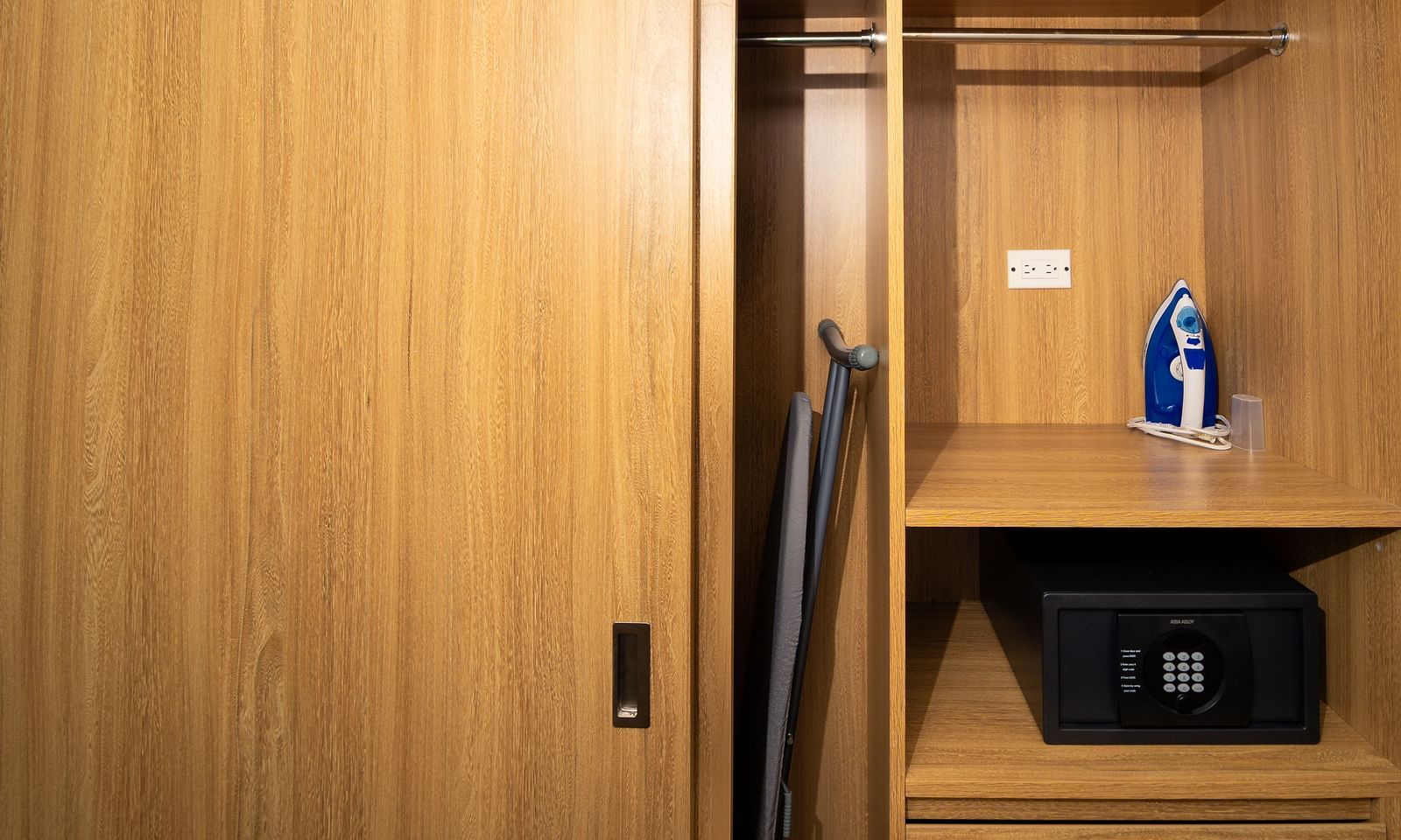 A closet in a hotel room in Montego Bay with a mini-safe tucked inside, an iron & ironing board - Hotel 39, Jamaica (Montego Bay)