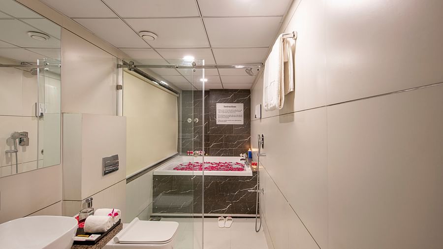 A well-lit hotel bathroom features a modern sink, toilet, and a bathtub - SK Lords Inn Ahmedabad