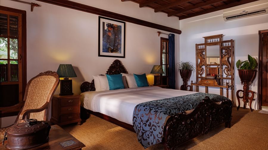 A room with a bed, a wooden dresser, a chair, and a coffee table - BluSalzz Villas - Muhamma Resort, Alleppey