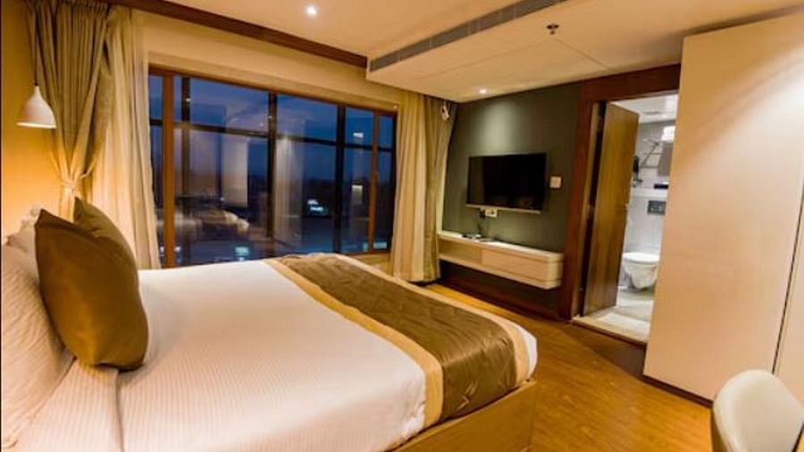 Deluxe hotel room with a large bed, a wall-mounted television, and windows to the side of the bed at Yashshree The Imperial Inn, Siliguri.