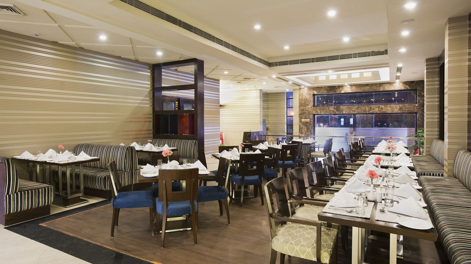 A closed dining space at The Manor Bareilly featuring multiple wooden tables and chairs arranged for a dining experience
