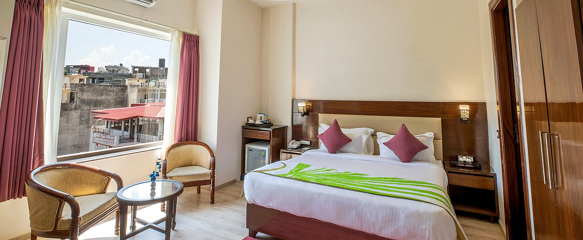 Full view shot of the Deluxe room featuring a double bed along with beautiful city views from the window at Regenta Inn DLS.