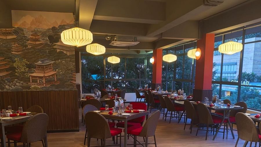 A cosy dining area with tables set for guests, featuring stylish lighting and a comfortable atmosphere for a pleasant meal.