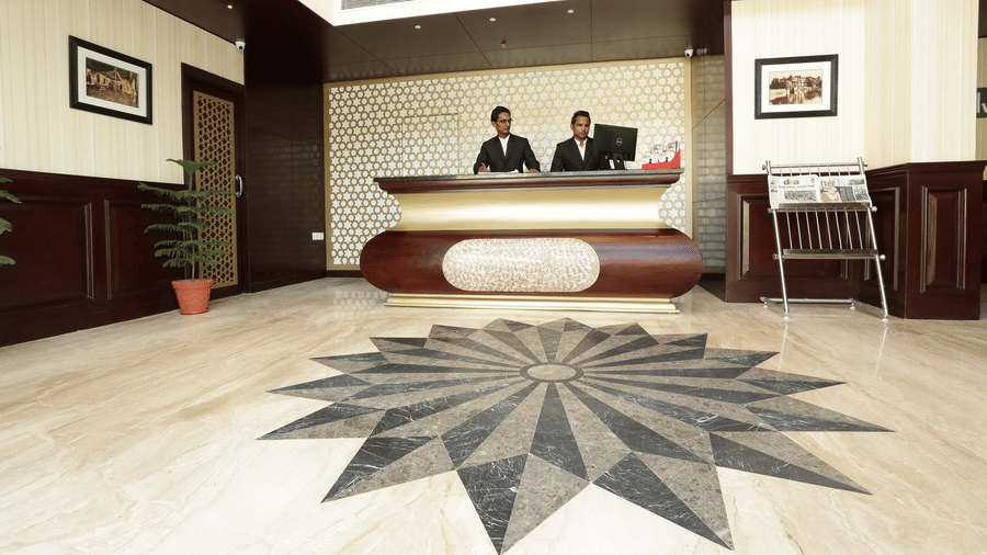 Lobby at Comfort Inn Sapphire by Eastlynn Collections, Jaipur with reception desk, staff, chair, and decorative floor pattern.