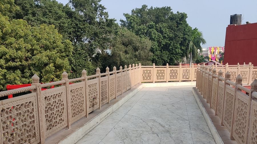 A corridor with marble tiles along with beige coloured traditional railings with lush green trees at one side - Hotel Gold, Panipat