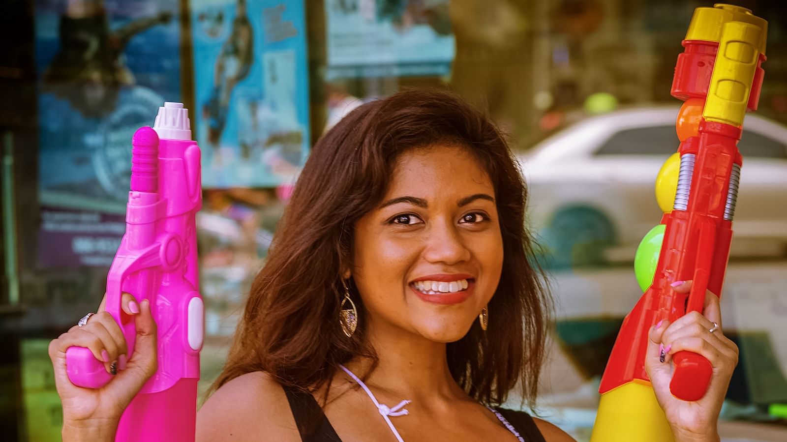 A portrait picture of a Thai girl holding two water guns and posing during Siam Songkran Festival.