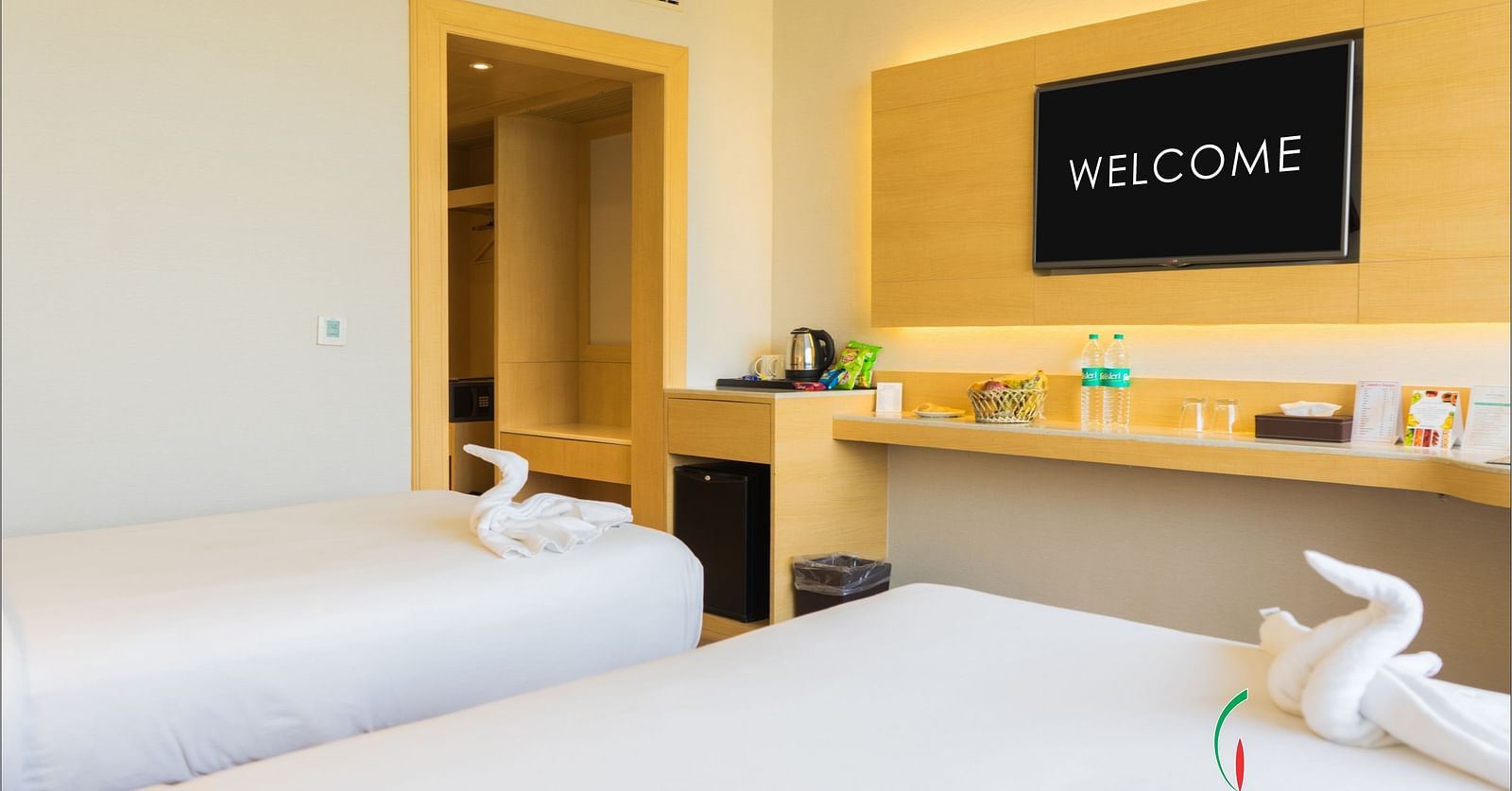 Twin beds with white linens in a room that has a desk and wall-mounted TV | Gemini Continental