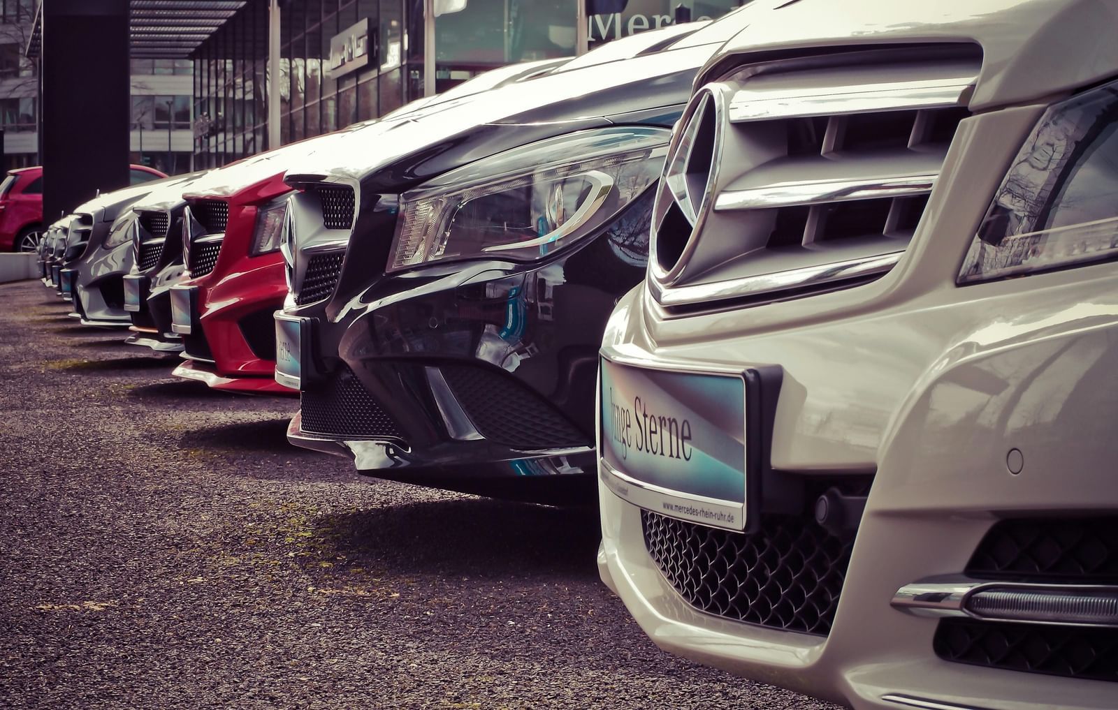 A row of parked cars of various colours in a lot.