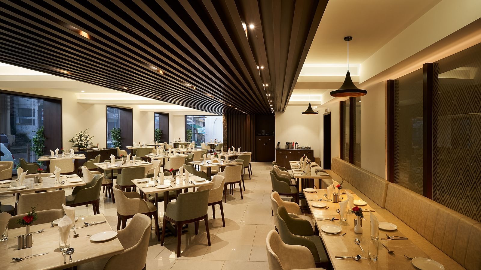 Spacious dining area with tables and chairs on one side, and seats along the wall on the other at The Hamuse Hotel, Kodaikanal.