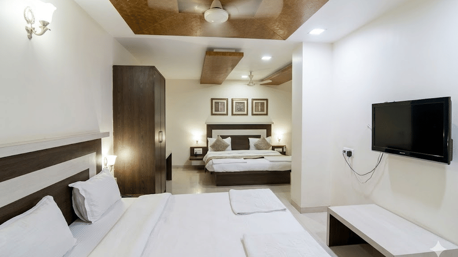 Modern hotel family room featuring a flat-screen TV mounted on the wall and crisp white bedding.