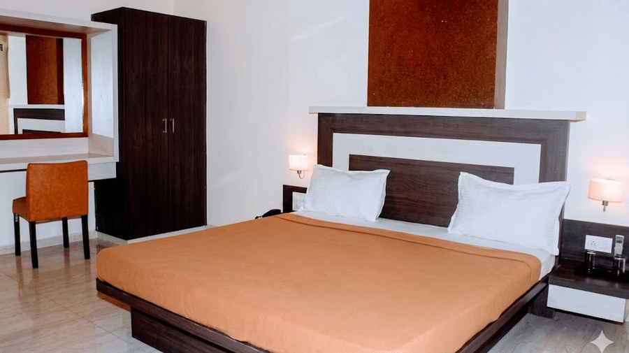 Hotel bedroom featuring a double bed with a brown bedspread, a matching dark wardrobe, and a vanity mirror.