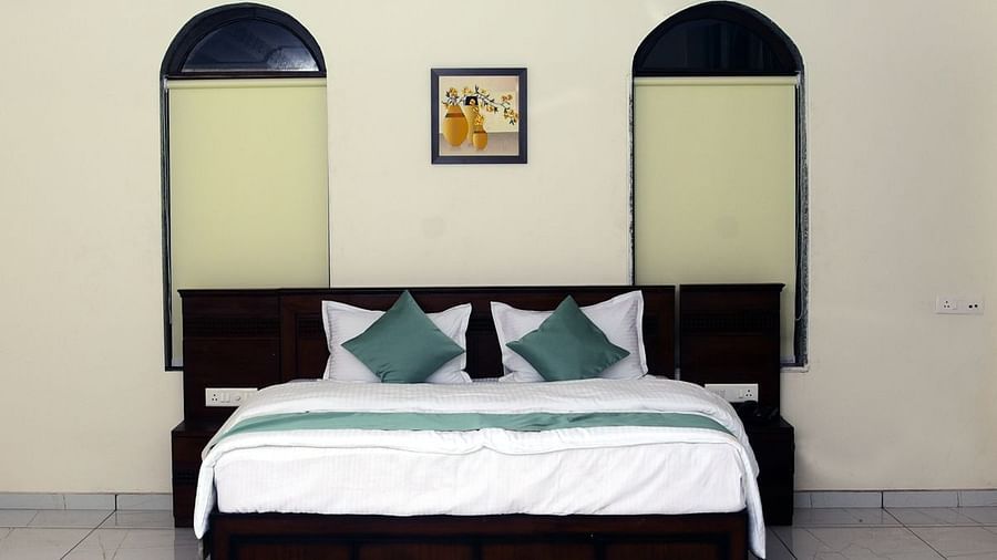 A front-view of a bed with white sheets and green pillows - VITS ExcellenSea, Dapoli