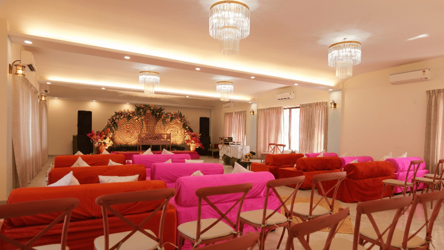 Chandeliers and floral stage decor in the Aarohi event hall at Grassfield Riviera Resort, a wedding venue near Jaipur.