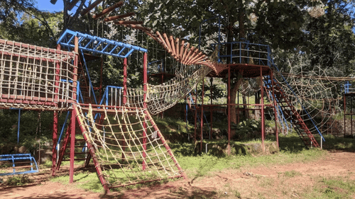 Outdoor play area with climbing frames and ropes for children.