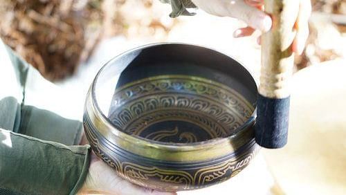A detailed shot of a person performing sound healing using a Tibetan bowl - Brewery Gulch Inn & Spa
