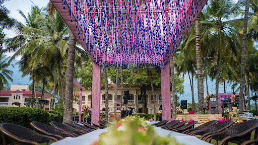 Floral-decorated canopy with vibrant purple and pink flowers, set up as an entryway to an outdoor event venue surrounded by palm trees - Black Thunder, Coimbatore