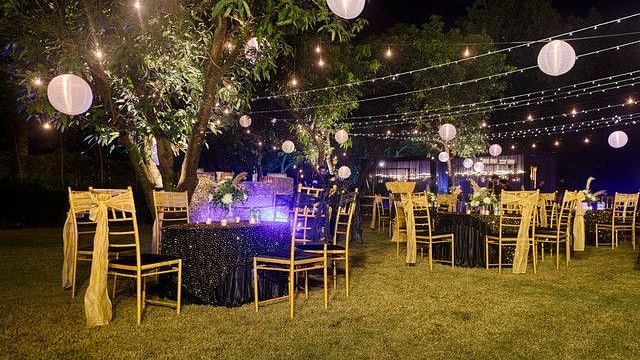 alt-text Outdoor event space with string lights and greenery.