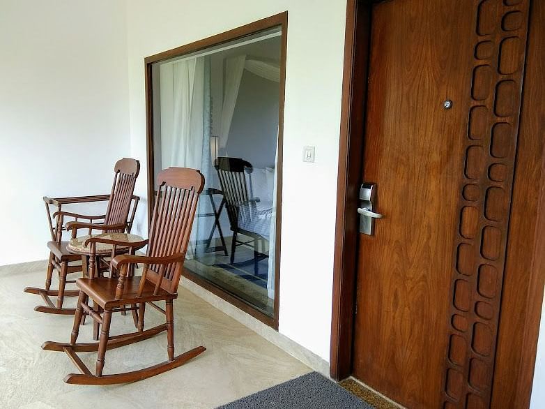 Entrance of a room with two wooden chairs and a wooden door.