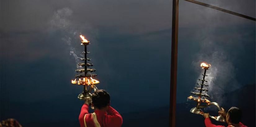 A person holding a traditional Indian lamp with multiple flames, creating a beautiful pattern of light and smoke.