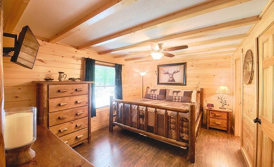 full view image of a bedroom featuring a cozy double bed with a beautiful picture wall mounted behind it - Historic Tapoco Lodge