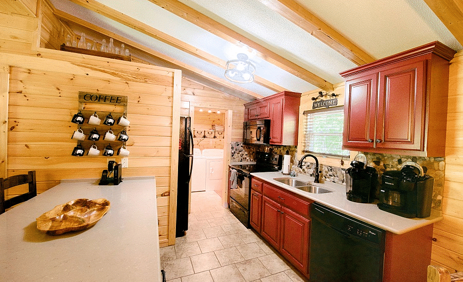 a fully equipped kitchen with red and black colored cabinets and modern appliances kept over a white counter top - Historic Tapoco Lodge