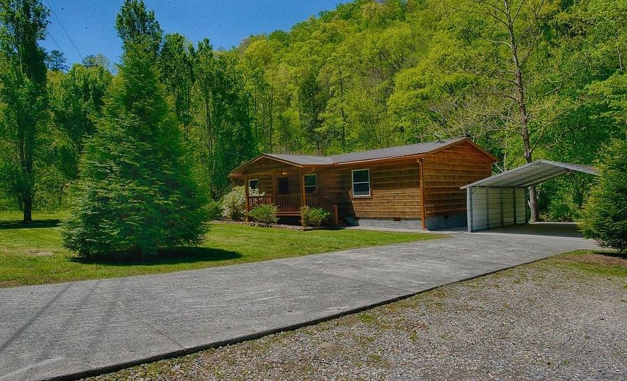 exterior shot of the river cabin taken from a distance featuring a huge evergreen conifer tree in front of it - Historic Tapoco Lodge