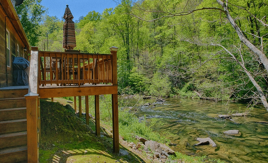 a wooden porch overlooking the Cheoah river and the surrounding greenery - Historic Tapoco Lodge