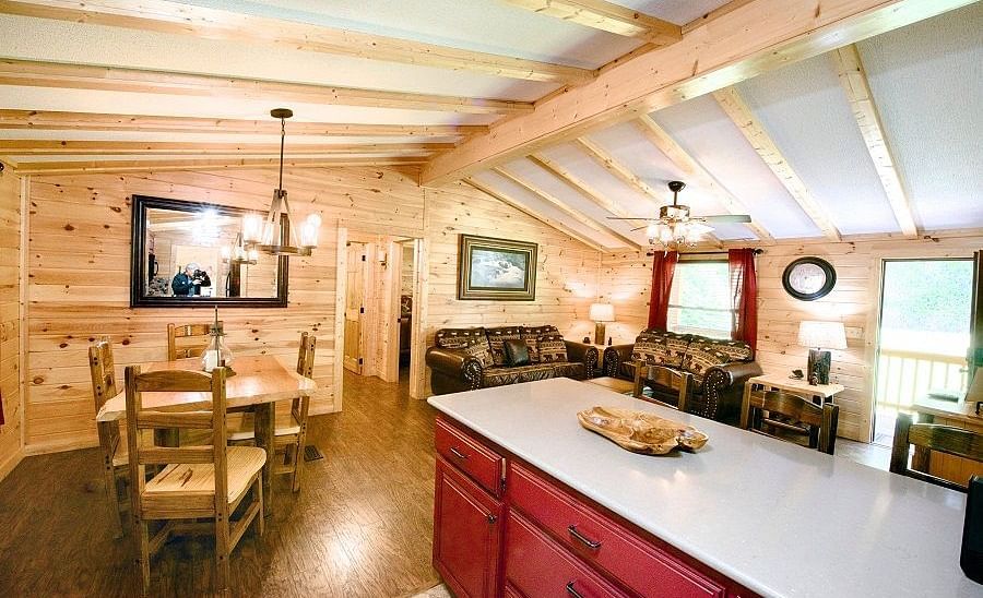 a white kitchen counter top with red colored shelves along with a dining area featuring a chandelier right above it - Historic Tapoco Lodge