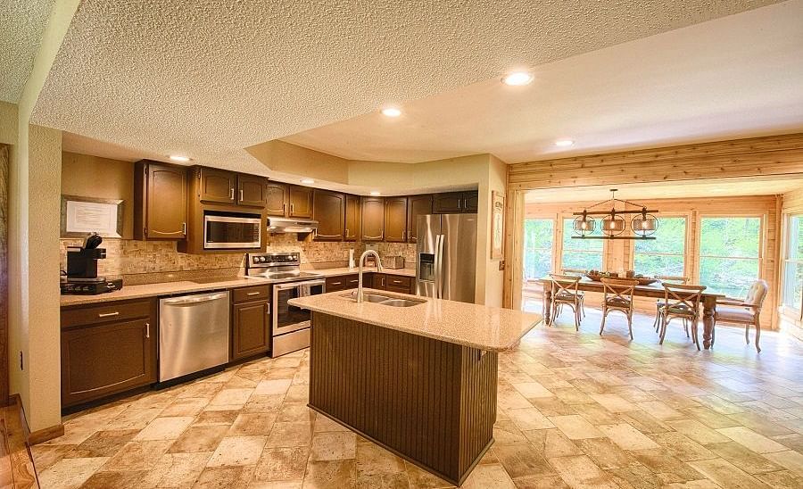 a well equipped kitchen with a service counter in the center along with the dining area in the far end - Historic Tapoco Lodge