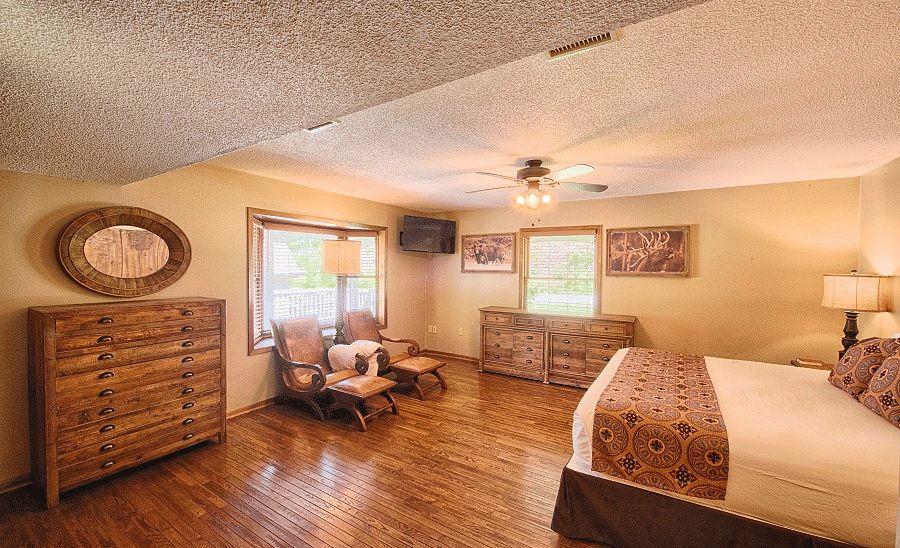 a room featuring a double bed and two reclining arm chairs along with a big wooden cupboard - Historic Tapoco Lodge