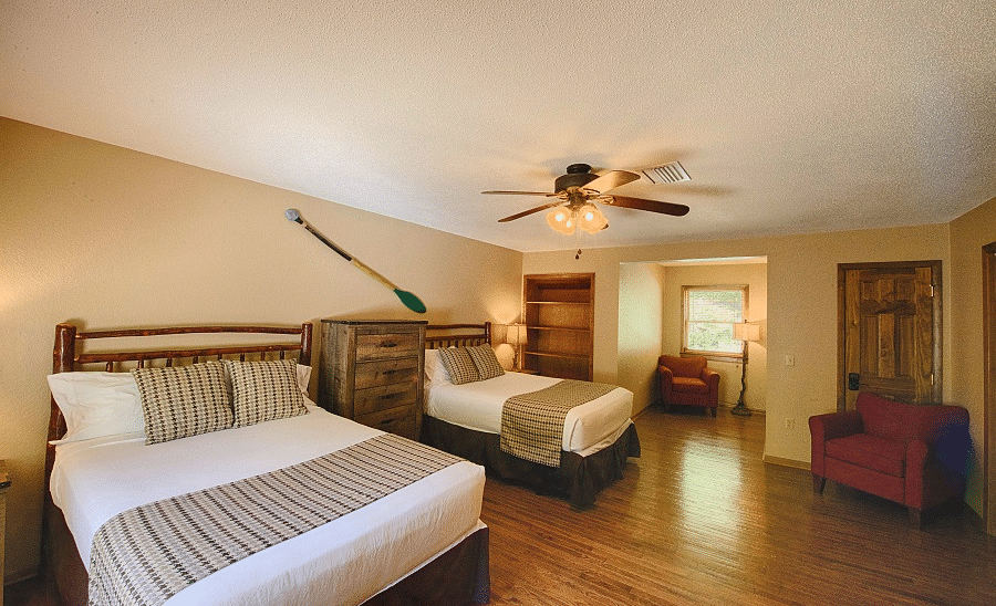 two double beds placed in a cozy room with a boat paddle hanging behind the beds - Historic Tapoco Lodge