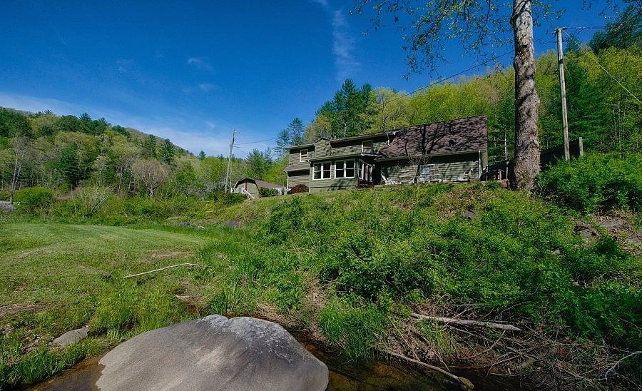 exterior image of the river house overlooking a lush green estate with a clear blue sky in the background - Historic Tapoco Lodge