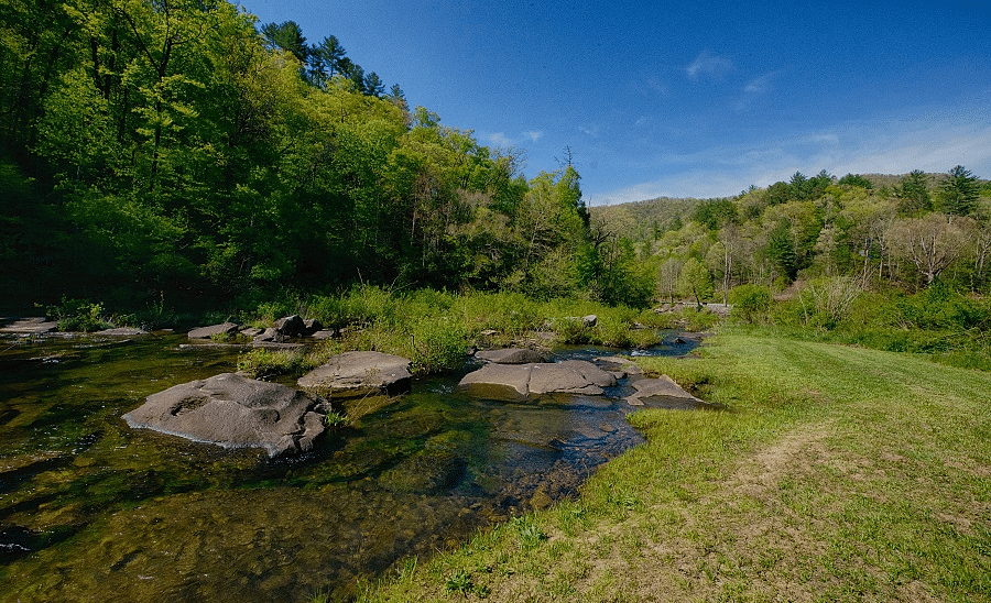 a small pond surrounded by huge rocks and a variety of trees - Historic Tapoco Lodge