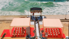 A beachfront wedding setup with a floral arch, chairs neatly arranged on a red carpet, and a scenic ocean backdrop at Uday Samudra Leisure Beach Hotel