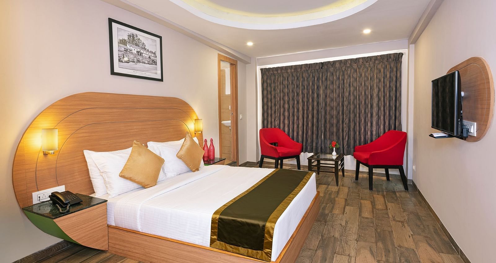 An image of a bedrom with dube sized bed and chairs on a different corner  | Mango HIll Central, Ooty