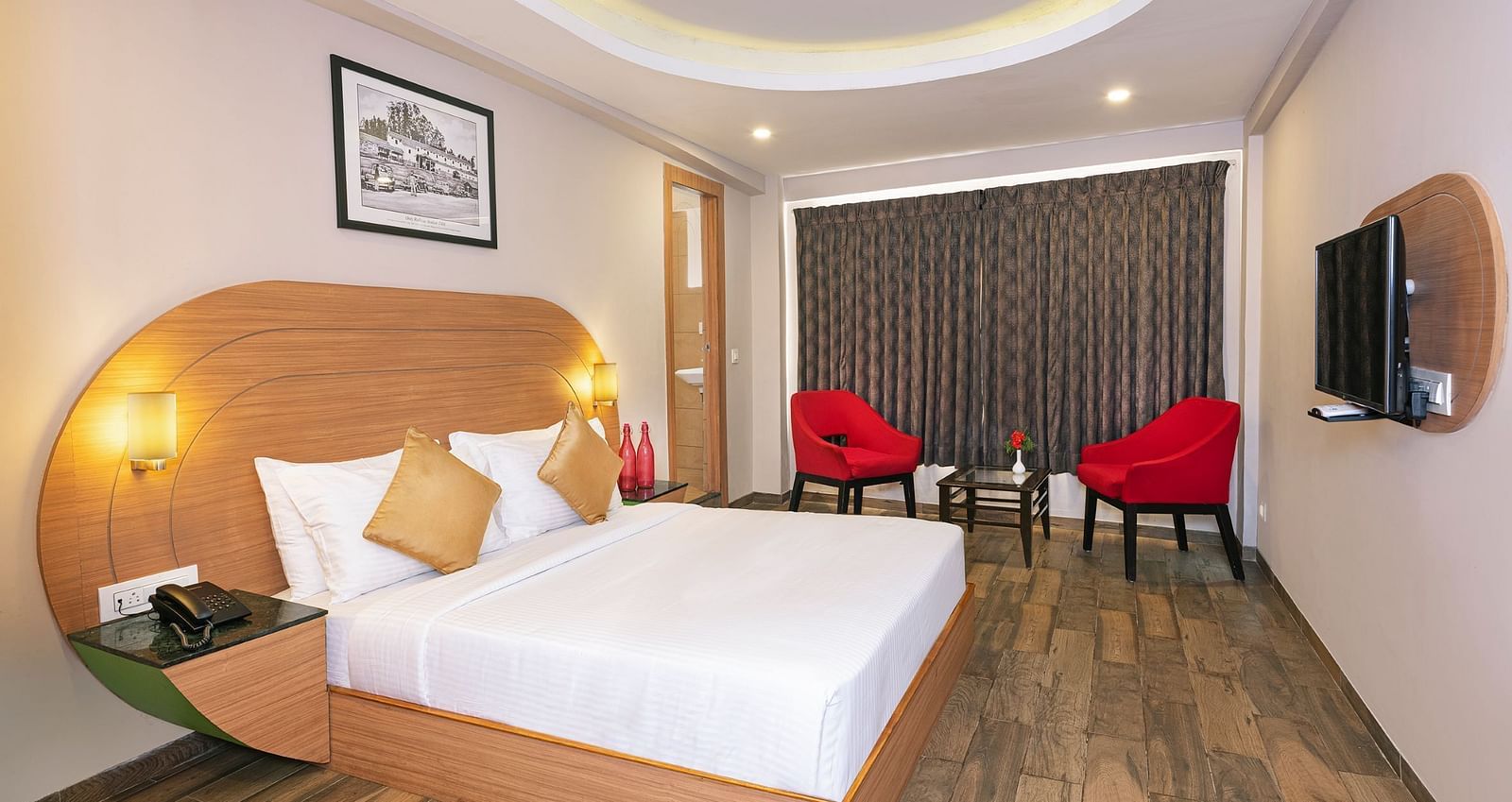 An image of a bedrom with dube sized bed and chairs on a different corner  | Mango HIll Central, Ooty
