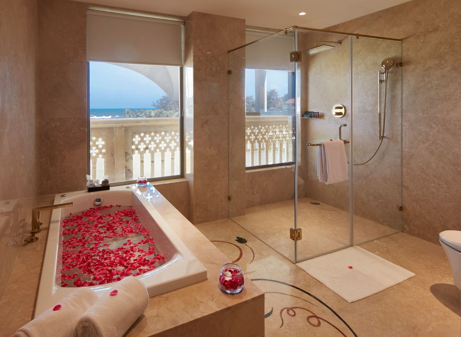 A luxurious bathroom with a petal-decorated bathtub and large glass shower enclosure - Kaldan Samudhra