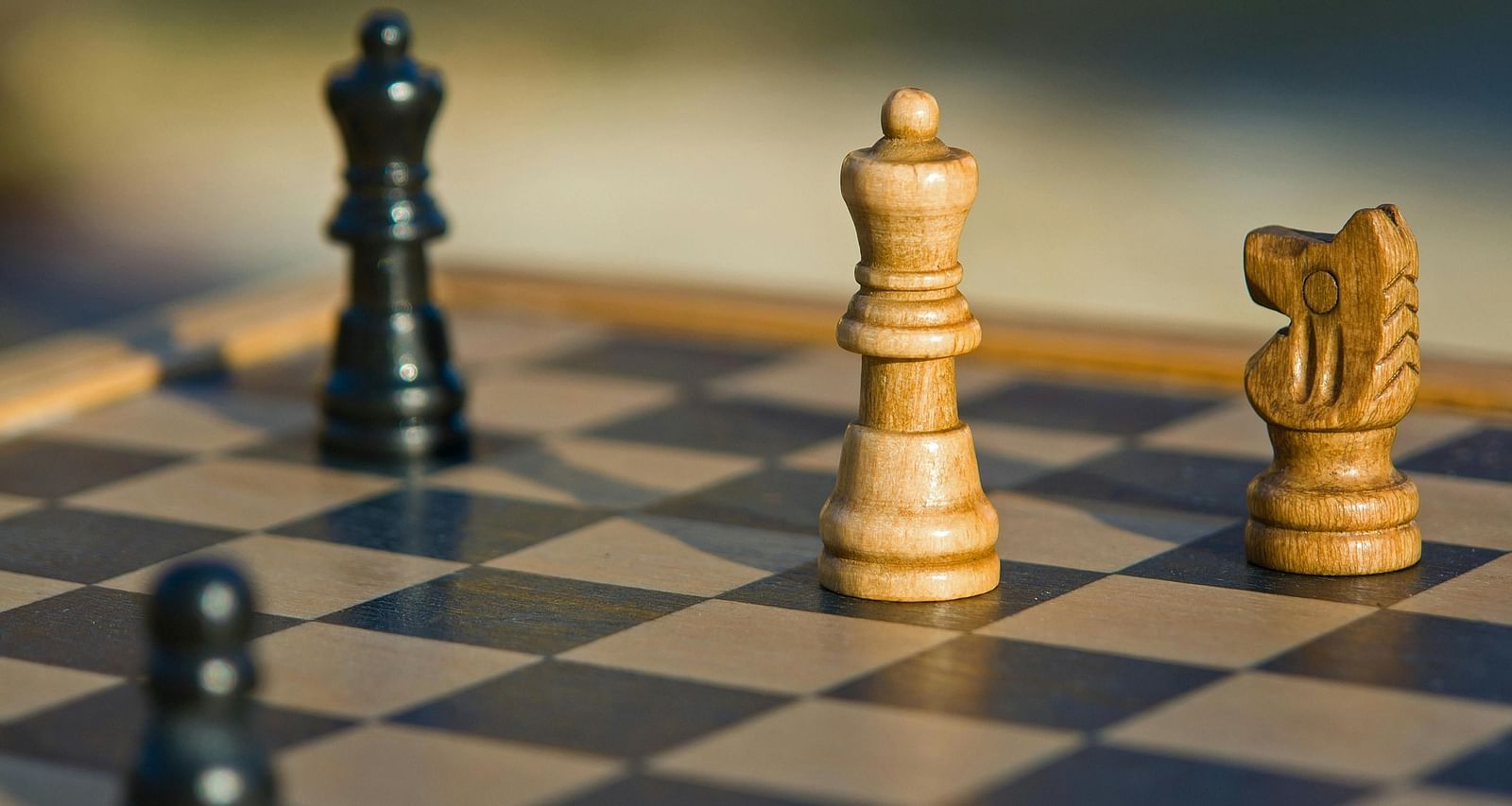 a wooden chess board with four chess pieces